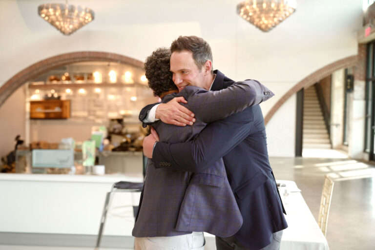 Two people hugging after a speaking engagement, celebrating a meaningful moment between a motivational speaker and an attendee.