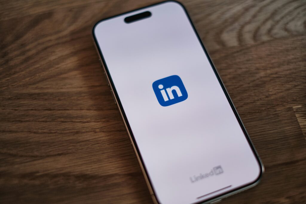 LinkedIn app open on a smartphone resting on a wooden surface, representing the platform where nonfiction authors build thought leadership and book visibility.