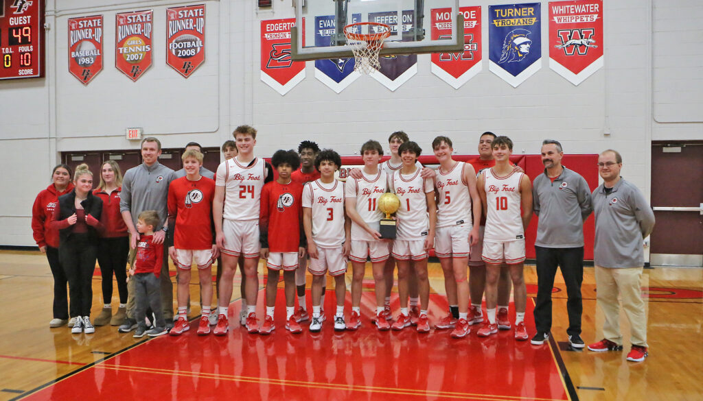 Photo of Hunter Price smiling with the Big Foot basketball team holding a trophy on their home court, coaching book for coaches.