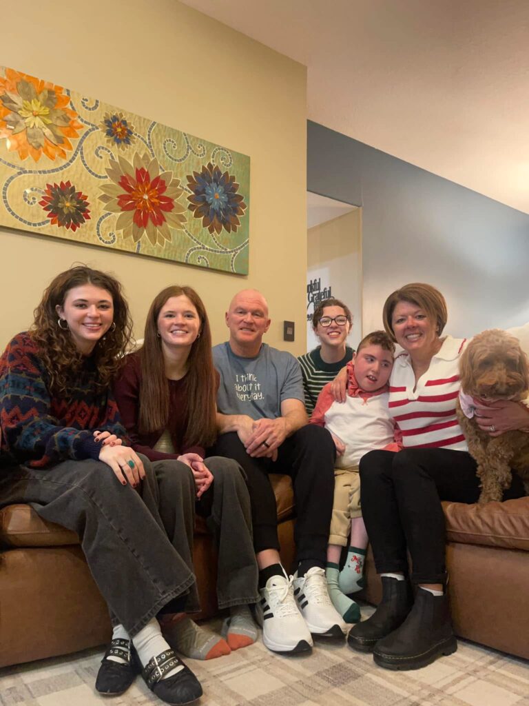Photo of Wes Bruns smiling with family on a couch, carbon monoxide survivor and author