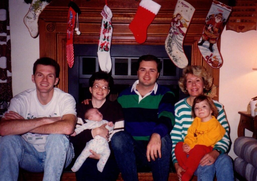 Family Christmas photo of Wes Bruns with relatives seated by stockings
