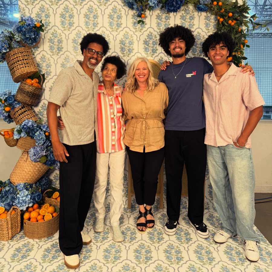 Photo of Bradley Rapier smiling with family members in front of a floral, citrus-themed backdrop