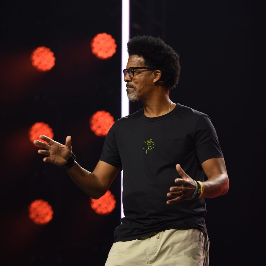 Photo of Bradley Rapier mid-gesture on stage in a headset mic, freestyle leadership book author speaking